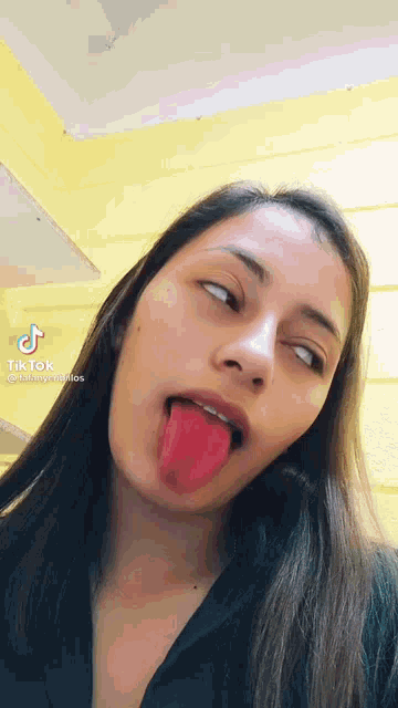 a woman is sticking her tongue out in a tik tok video .