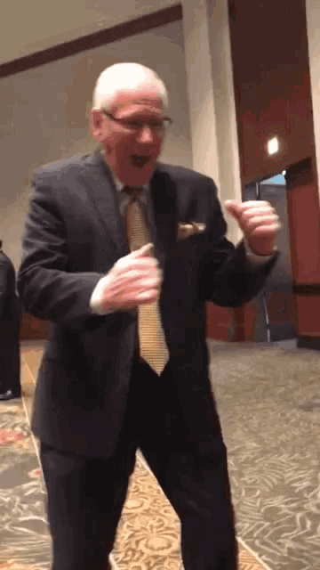 a man in a suit and tie is dancing with his hands in the air