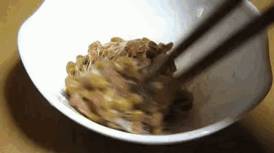 a bowl of food with chopsticks in it on a table