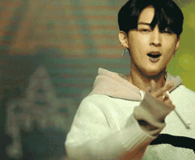a young man wearing a white sweater and a pink hoodie is making a funny face