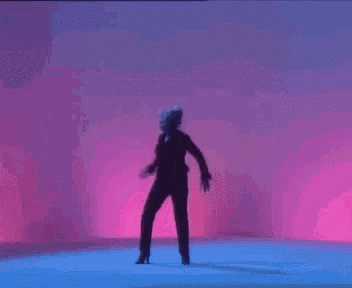 a woman is dancing in a dark room with purple and blue lights .