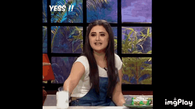 a woman is sitting at a table with a cup of coffee and the words yess on the screen