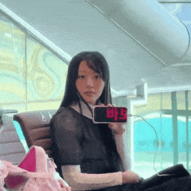 a woman sitting in a chair holding a phone that says bts on it