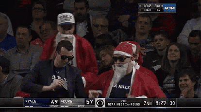 a man in a santa costume is sitting in the stands watching a game between yale and duke