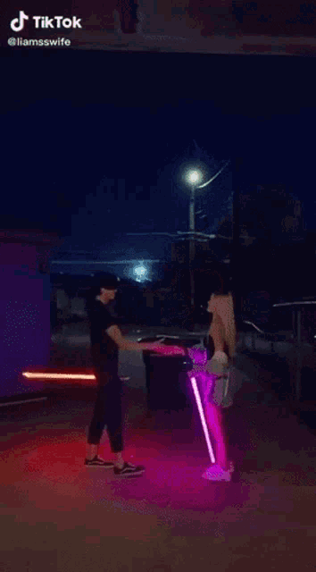 a man and a woman are standing next to each other with lightsabers on their legs .