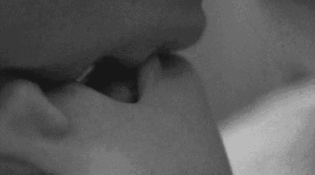 a black and white photo of a person kissing another person 's hand .