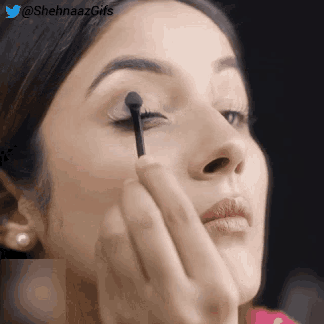 a close up of a woman applying makeup with the hashtag @shehnaazgifs on the bottom