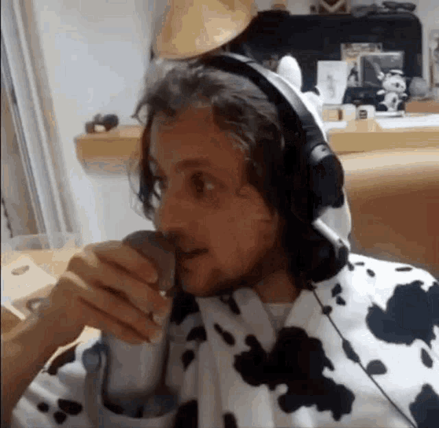 a man wearing headphones and a cow costume is holding a microphone .