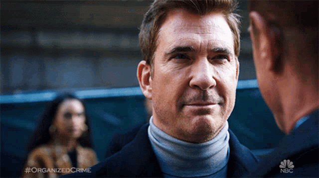 a man in a turtleneck is talking to another man in a nbc ad