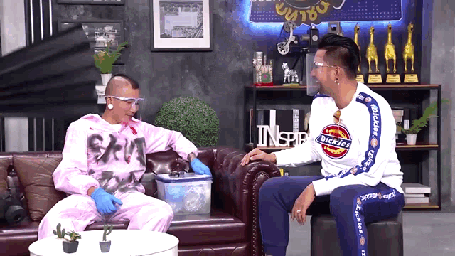 a man wearing a dickies shirt sits next to another man on a couch