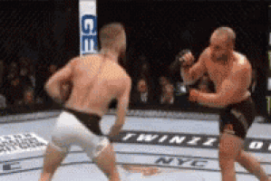 two men are fighting in a boxing ring with a sign that says geico on it .