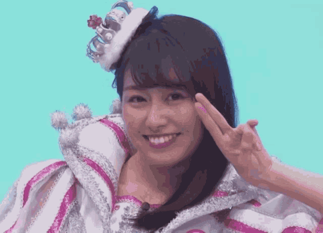 a woman with a crown on her head is smiling and giving the peace sign