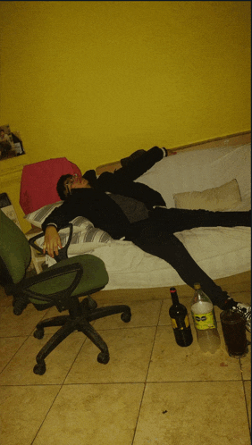 a man is laying on a couch with a bottle of coca cola on the floor