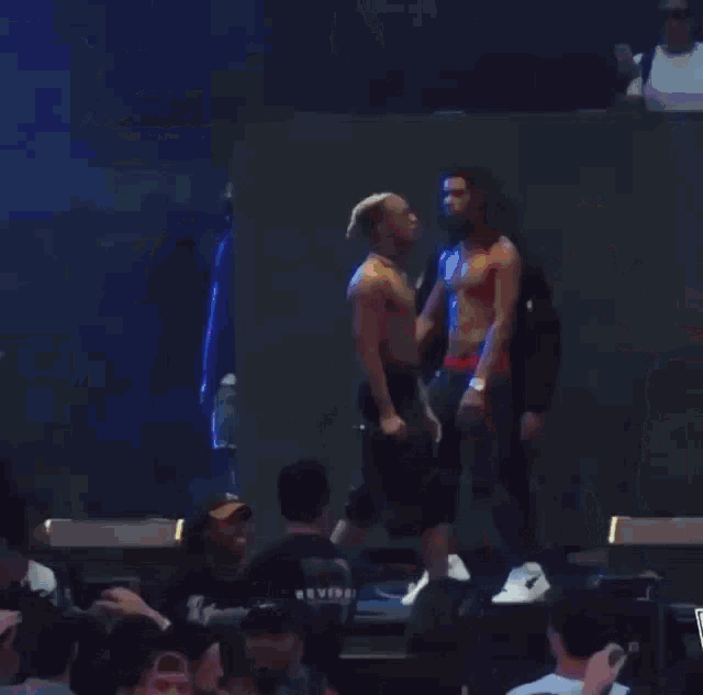 a group of men are standing on a stage with a supreme logo in the back