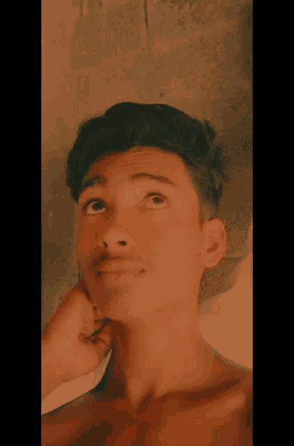 a young man without a shirt is taking a selfie with his hand on his neck