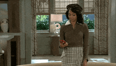 a woman wearing a plaid skirt and a beret is holding a cell phone