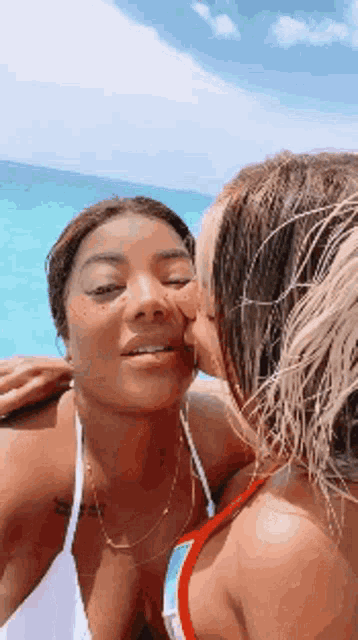 a woman is kissing another woman on the cheek while taking a selfie .