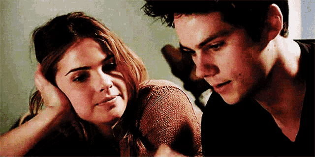 a man and a woman are looking at each other and the woman is touching the man 's head .