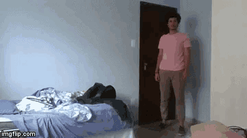 a man in a pink shirt is standing in front of a bedroom door