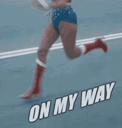 a woman in a wonder woman costume is running on a road with the words on my way below her .