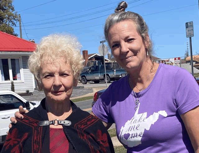 two women standing next to each other one wearing a take me home shirt