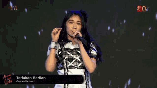 a girl is singing into a microphone with the words teriak berlian on the screen