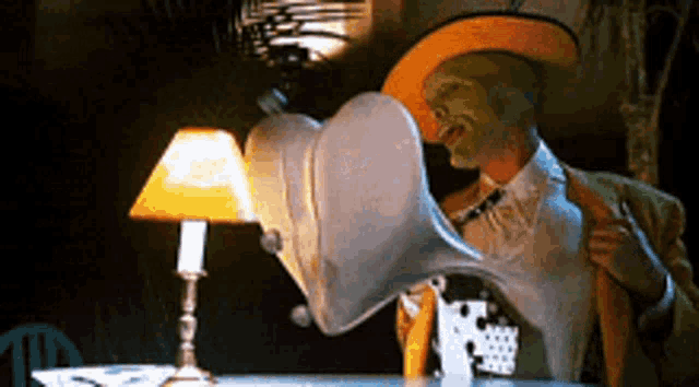 a man with a mask on his face is sitting at a table with a lamp on it