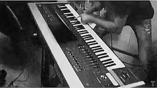 a black and white photo of a man playing a piano .