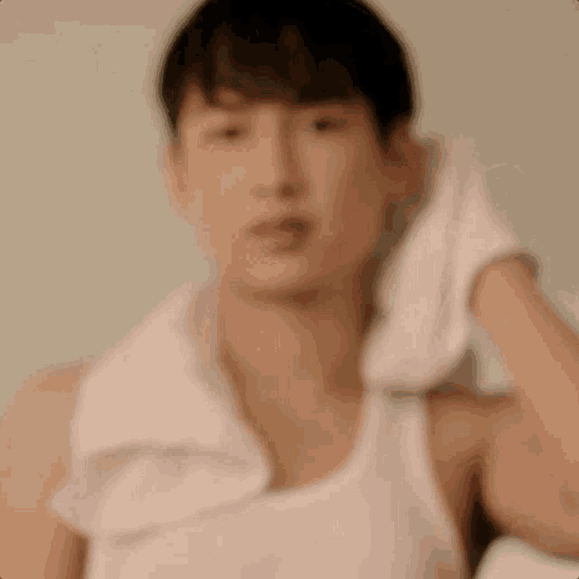 a blurry picture of a man wearing a white tank top and a towel around his neck .