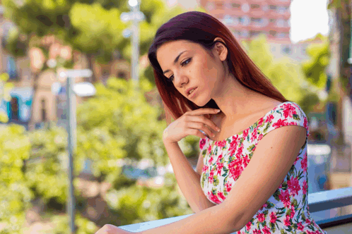 a woman in a pink and white floral dress looks down