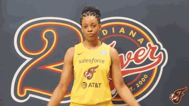 a woman in a yellow salesforce jersey stands in front of a diana flyers sign