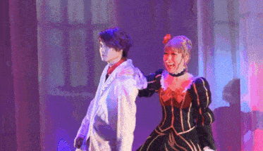 a man and a woman are dancing on a stage with purple lights .