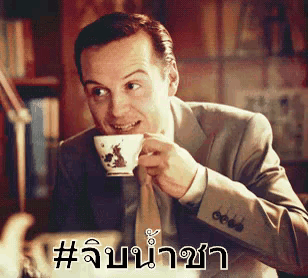 a man in a suit and tie is drinking a cup of coffee