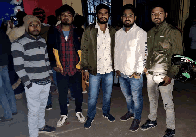 a man wearing a tommy jeans jacket poses with his friends