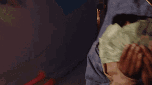 a person is holding a bunch of money in front of their face