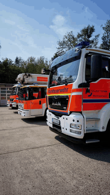a row of fire trucks are parked in a parking lot and one of them says man