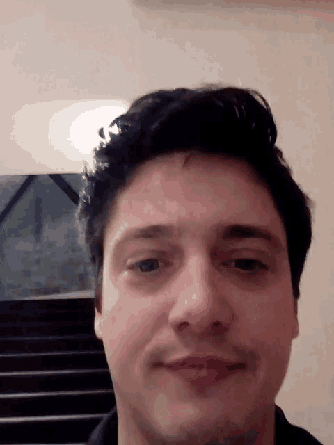 a close up of a man 's face with stairs behind him