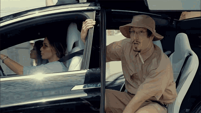 a man in a hat is sitting in a car with a woman driving