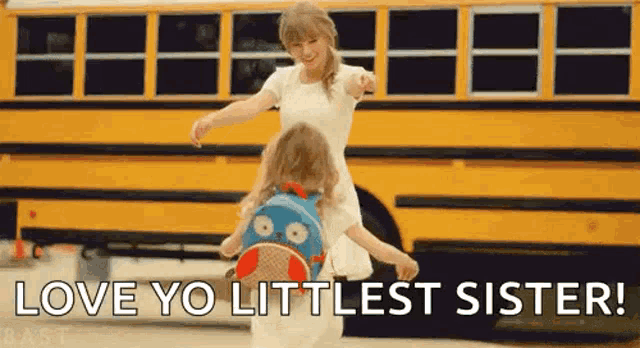 a woman is holding a little girl on her shoulders in front of a school bus .