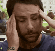 a man with a beard is holding his head in pain
