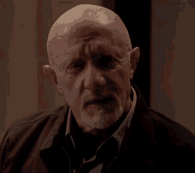 a bald man with a beard is wearing a black jacket