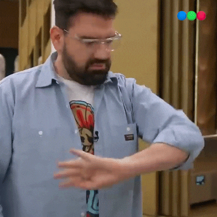a man with a beard wearing glasses and a blue shirt is standing in a kitchen .
