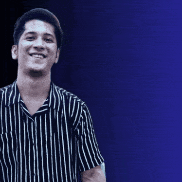a man in a black and white striped shirt smiles in front of a google logo