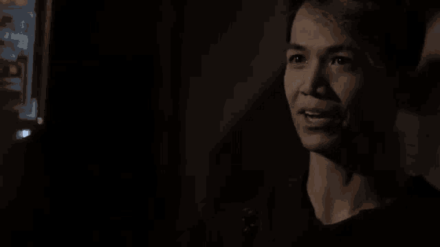 a young man is smiling in a dark room while looking at something .