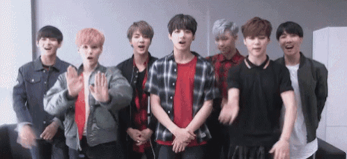 a group of young men are standing next to each other and waving .