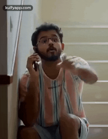 a man is talking on a cell phone while sitting on a set of stairs .