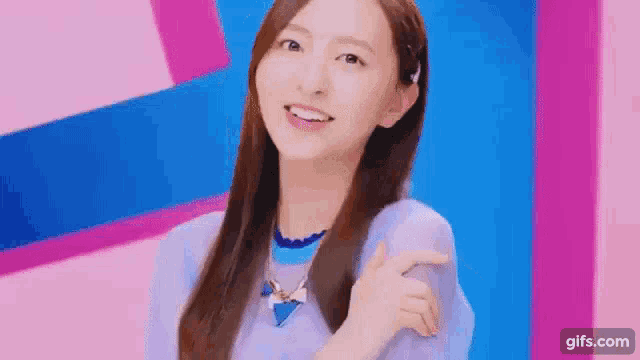 a young woman in a purple sweater is smiling and pointing at something .
