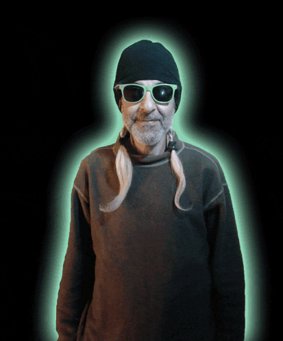 a man wearing sunglasses and a black hat stands in front of a black background