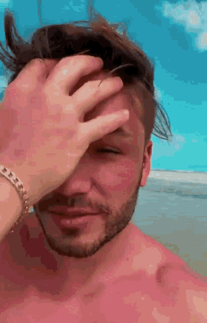 a man with a bracelet on his wrist covering his face with his hand