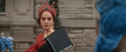 a woman in a red dress and red crown is holding a laptop .
